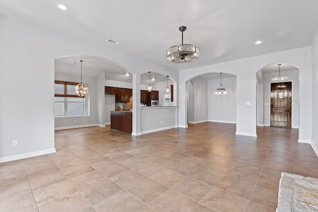 unfurnished living room with baseboards, recessed lighting, visible vents, and an inviting chandelier