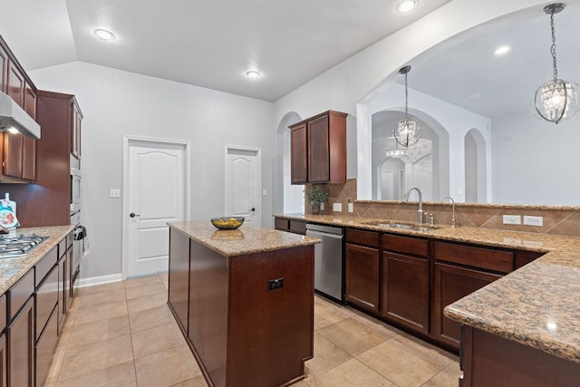 kitchen featuring light stone counters, stainless steel appliances, a kitchen island, a sink, and backsplash