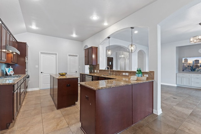 kitchen with arched walkways, a kitchen island, a sink, light stone countertops, and backsplash