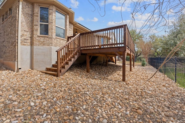 view of side of home with stairs, fence, a deck, and brick siding