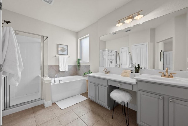 bathroom with double vanity, a stall shower, a sink, a bath, and tile patterned floors