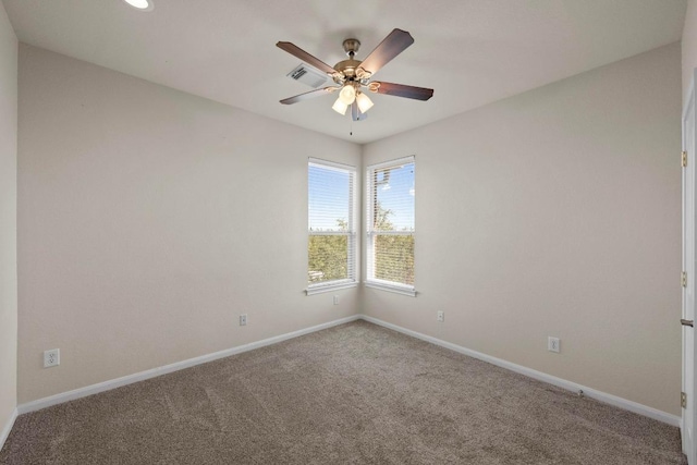 carpeted spare room with visible vents, a ceiling fan, and baseboards