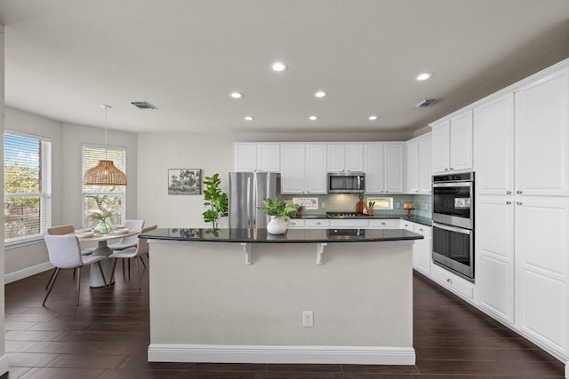 kitchen featuring appliances with stainless steel finishes, a kitchen island, visible vents, and decorative backsplash