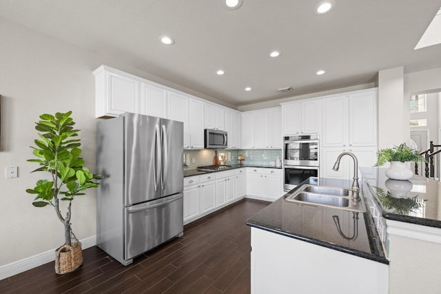 kitchen with dark wood finished floors, tasteful backsplash, appliances with stainless steel finishes, white cabinetry, and a sink