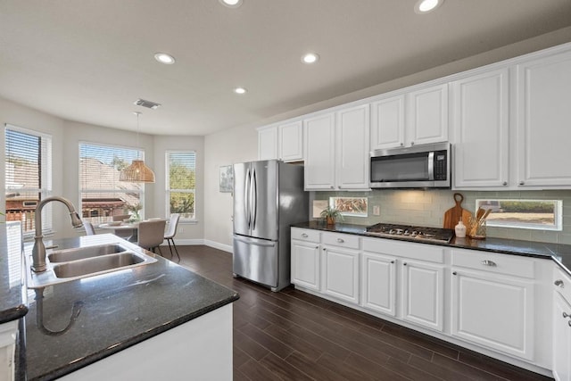 kitchen with stainless steel appliances, visible vents, backsplash, white cabinets, and a sink