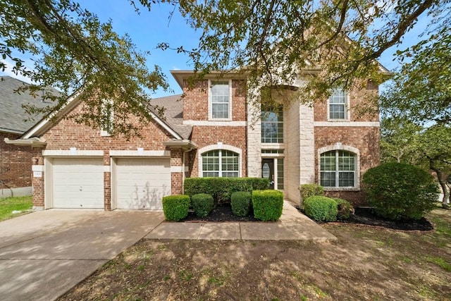 traditional-style home featuring a garage, concrete driveway, and brick siding