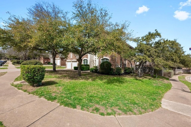 view of property hidden behind natural elements with a garage and a front yard