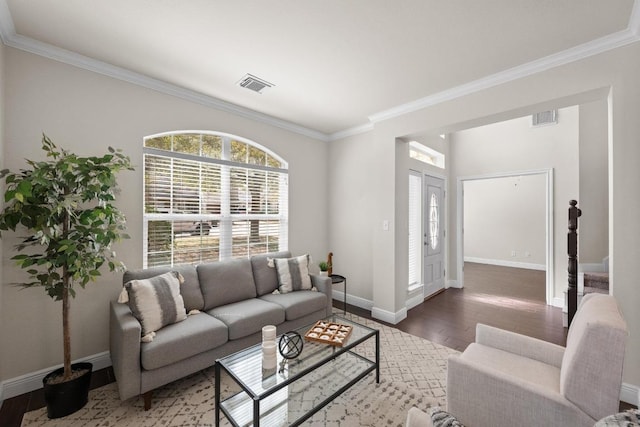 living room featuring baseboards, crown molding, visible vents, and wood finished floors