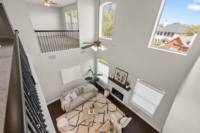 living room featuring a fireplace, visible vents, ceiling fan, wood finished floors, and baseboards