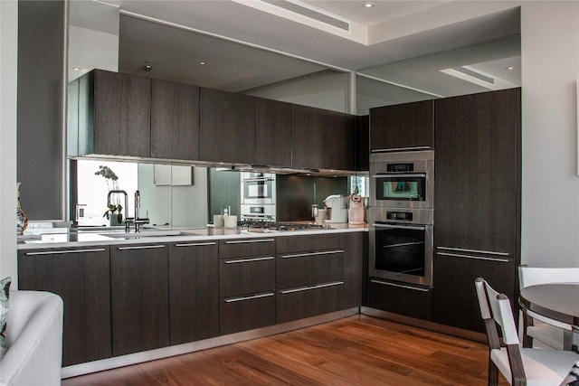 kitchen with light countertops, a sink, dark brown cabinetry, and modern cabinets