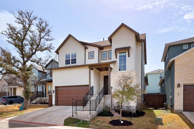 view of front of house with concrete driveway, an attached garage, fence, and stucco siding