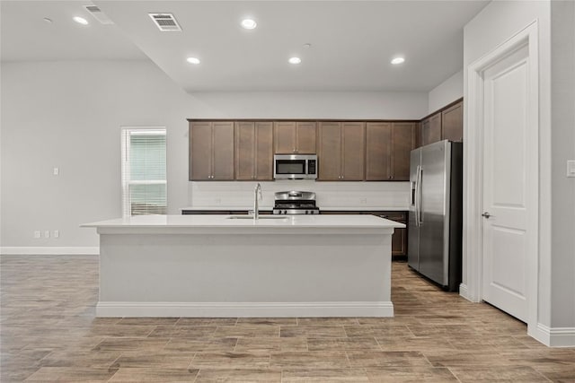 kitchen featuring light countertops, appliances with stainless steel finishes, an island with sink, and visible vents