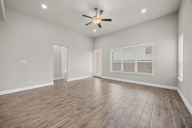 spare room featuring recessed lighting, wood finished floors, a ceiling fan, and baseboards