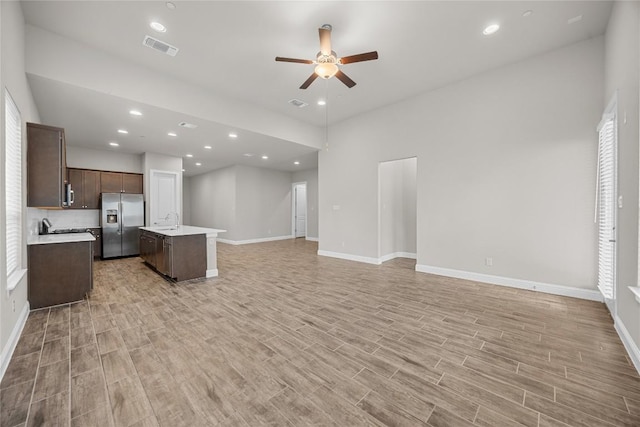 kitchen with stainless steel fridge, visible vents, open floor plan, light countertops, and dark brown cabinets