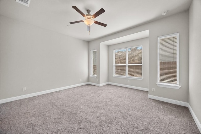 carpeted spare room with visible vents, ceiling fan, and baseboards