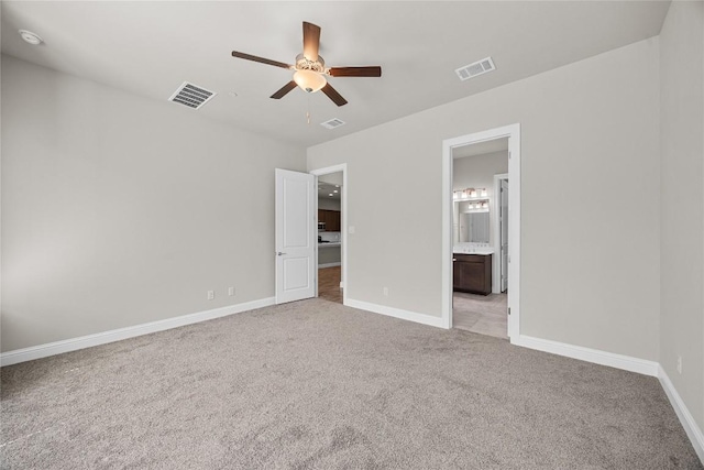 unfurnished bedroom with light carpet, ensuite bath, visible vents, and baseboards