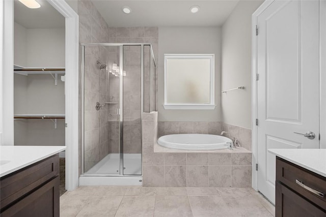 full bathroom with a spacious closet, a shower stall, and vanity