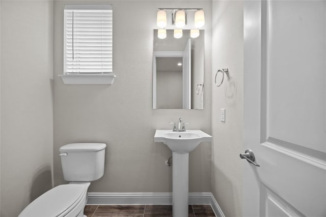 bathroom featuring a sink, wood finished floors, toilet, and baseboards