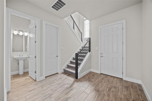 entryway with stairway, wood finished floors, visible vents, and baseboards