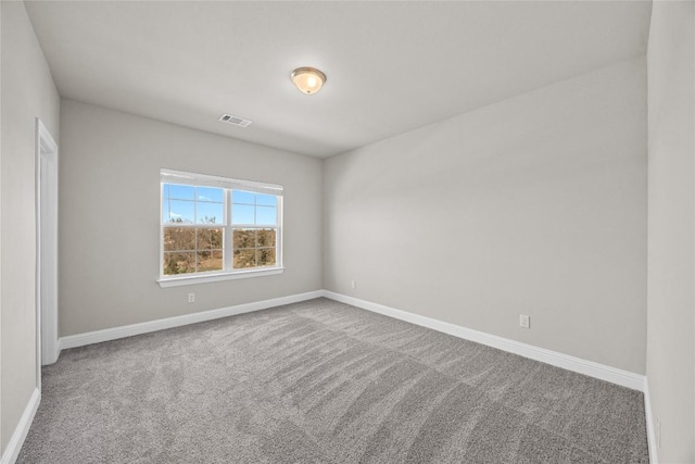 spare room featuring carpet, visible vents, and baseboards