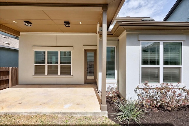 property entrance with a patio, fence, and stucco siding