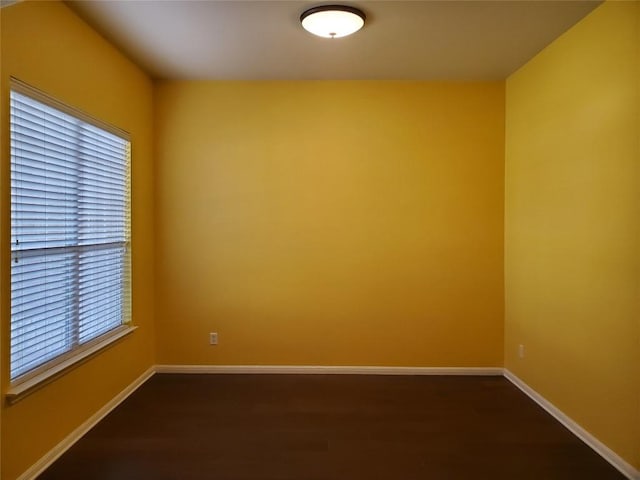 unfurnished room featuring dark wood-type flooring and baseboards