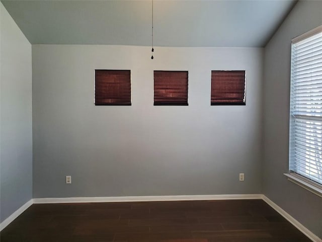 unfurnished room featuring baseboards and dark wood-style flooring