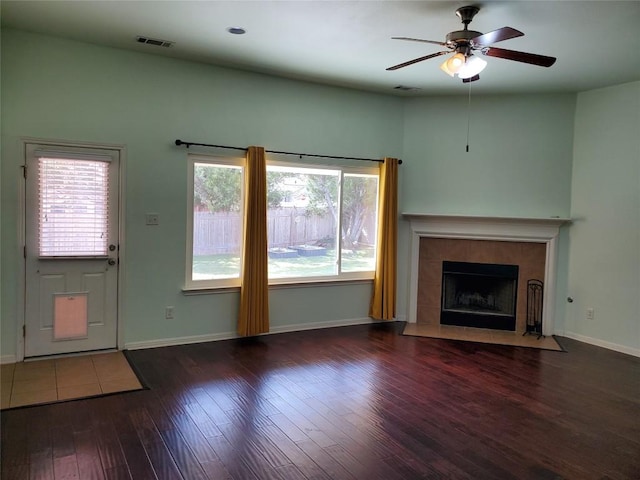 unfurnished living room with a fireplace, wood finished floors, visible vents, and baseboards