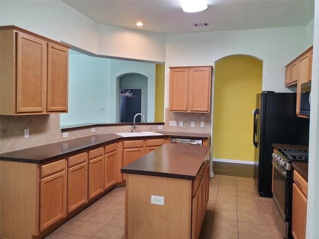 kitchen featuring a sink, dark countertops, appliances with stainless steel finishes, and light tile patterned flooring