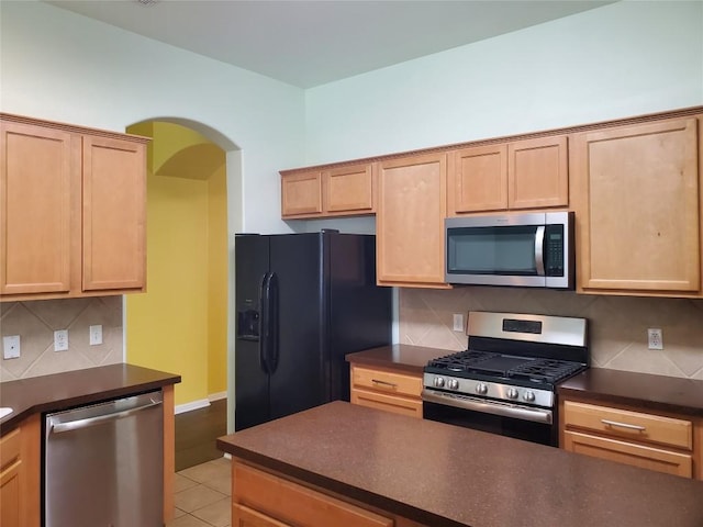 kitchen with dark countertops, light brown cabinets, and appliances with stainless steel finishes