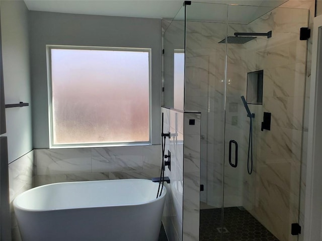 bathroom with a marble finish shower and a freestanding bath