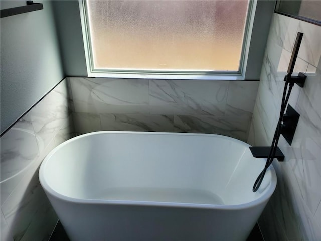 full bath featuring a soaking tub, plenty of natural light, and tile walls