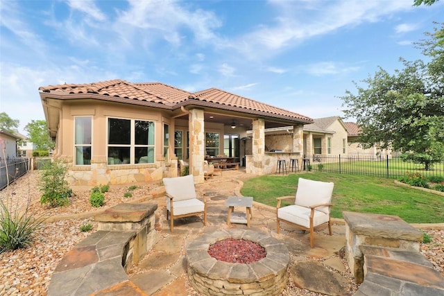rear view of property with stone siding, a patio area, a tiled roof, and a ceiling fan