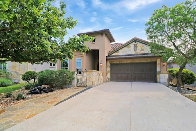 mediterranean / spanish-style home with stucco siding, stone siding, an attached garage, driveway, and a tile roof