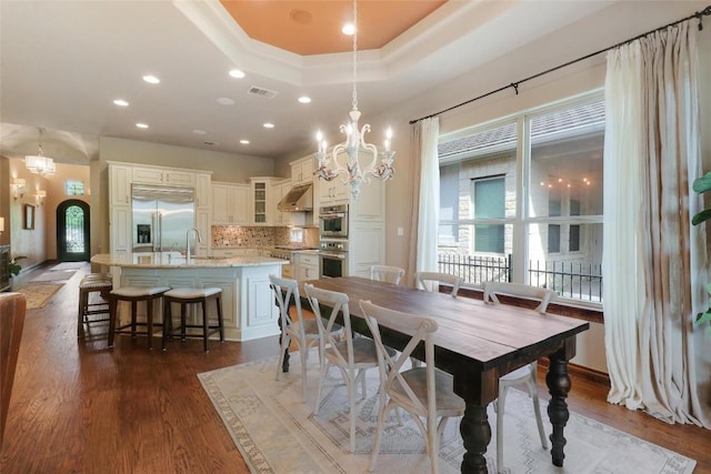 dining area featuring a chandelier, a tray ceiling, dark wood finished floors, and recessed lighting
