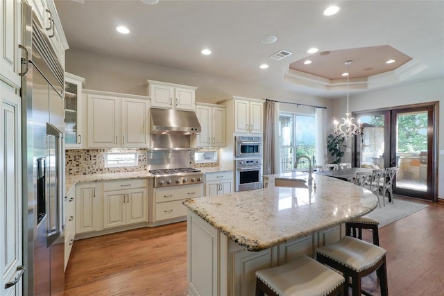 kitchen featuring appliances with stainless steel finishes, under cabinet range hood, light wood-style floors, a chandelier, and recessed lighting