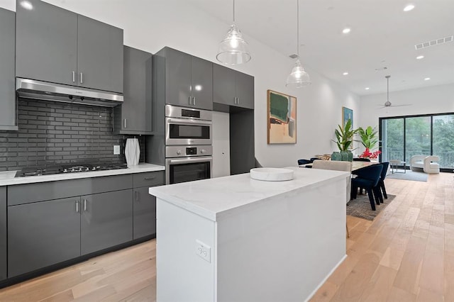 kitchen featuring visible vents, black cooktop, light wood-style flooring, gray cabinetry, and under cabinet range hood