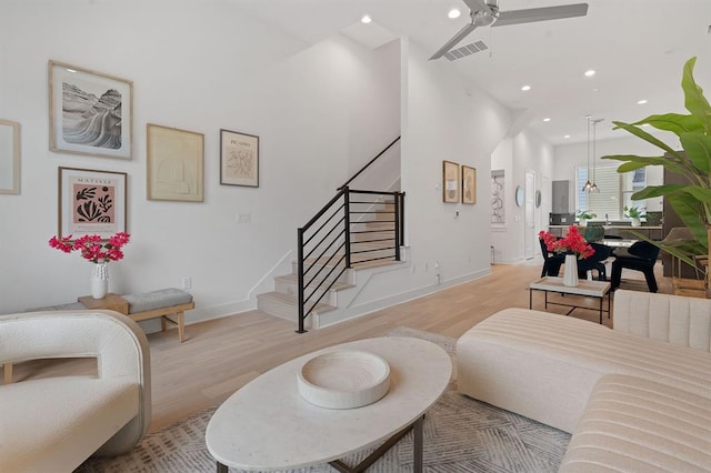 living area with visible vents, baseboards, light wood-style flooring, stairway, and recessed lighting