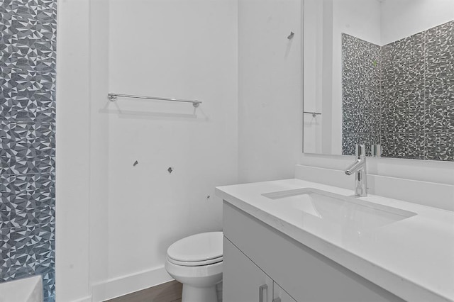 bathroom featuring baseboards, vanity, toilet, and wood finished floors