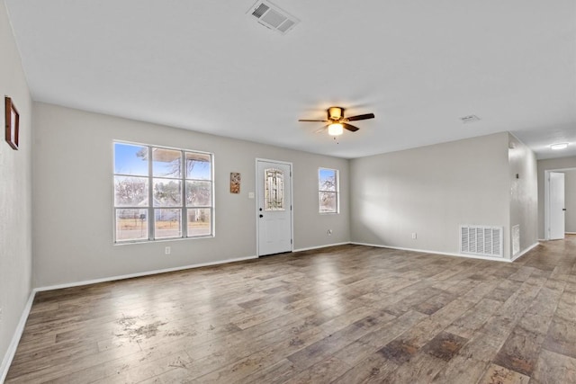 interior space featuring a ceiling fan, visible vents, and wood finished floors