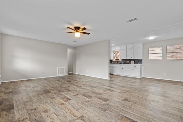 unfurnished living room with baseboards, visible vents, ceiling fan, and light wood finished floors