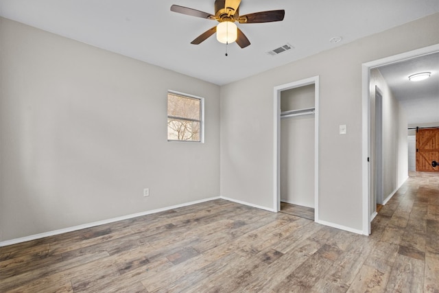 unfurnished bedroom featuring a closet, visible vents, ceiling fan, wood finished floors, and baseboards