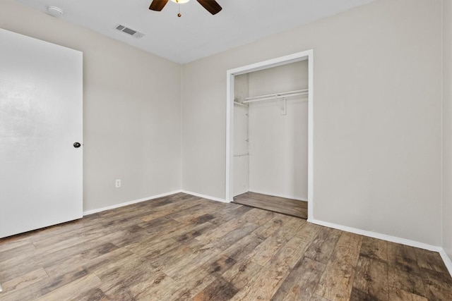 unfurnished bedroom featuring ceiling fan, wood finished floors, visible vents, baseboards, and a closet