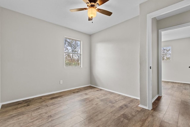 empty room with a healthy amount of sunlight, a ceiling fan, and wood finished floors