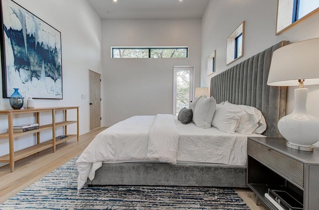 bedroom with light wood finished floors and a high ceiling