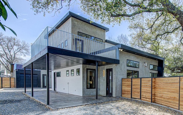 view of front of house with fence, a balcony, and stucco siding