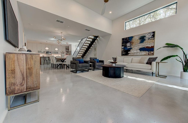 living area with recessed lighting, visible vents, a high ceiling, and stairs