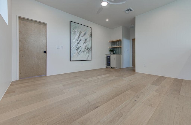 spare room with light wood-style flooring, wine cooler, visible vents, and ceiling fan