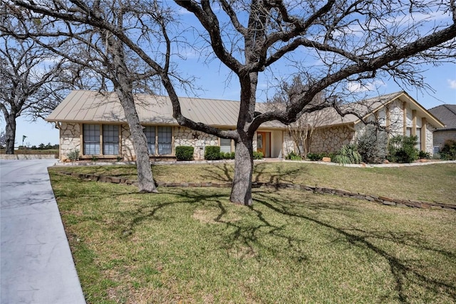 view of front of home with metal roof, stone siding, a front lawn, and a standing seam roof