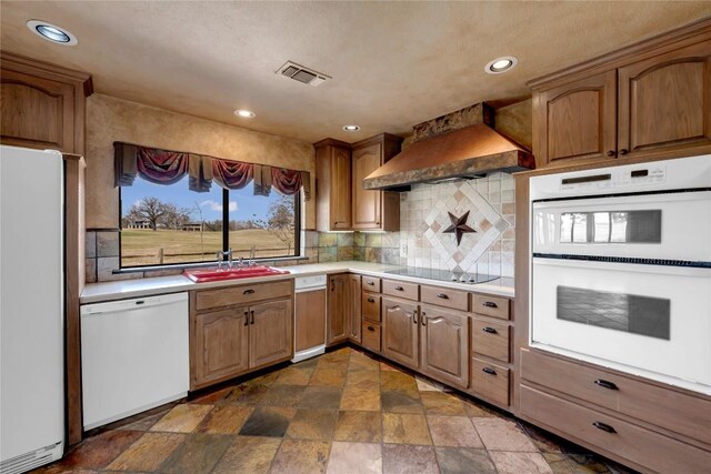 kitchen with white appliances, a sink, visible vents, light countertops, and custom range hood